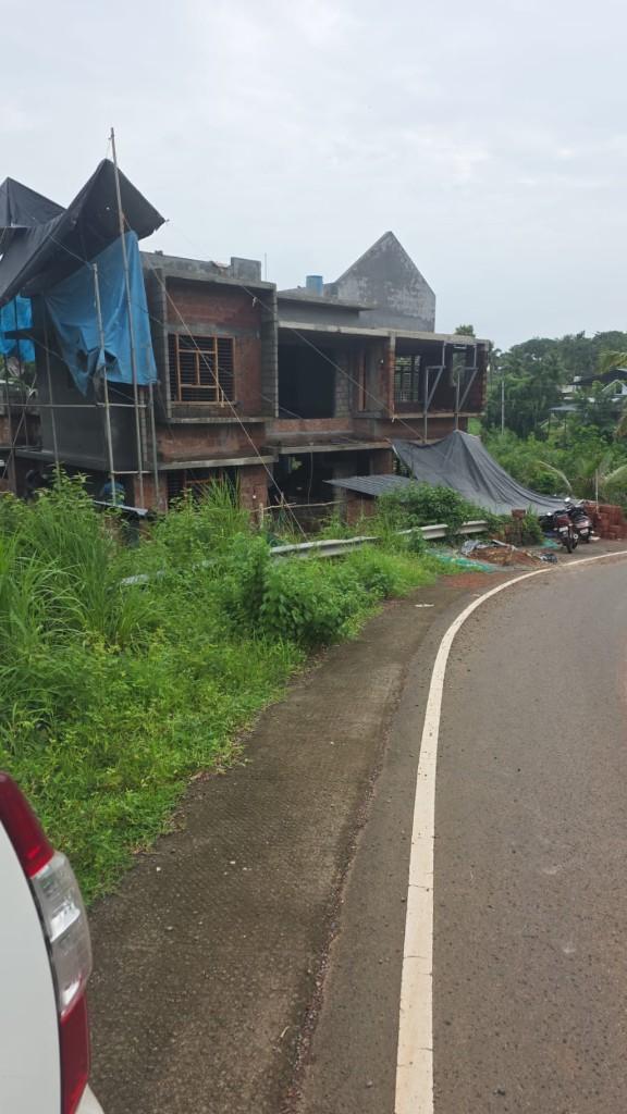 Multi-storey house under construction with laterite walls and scaffolding